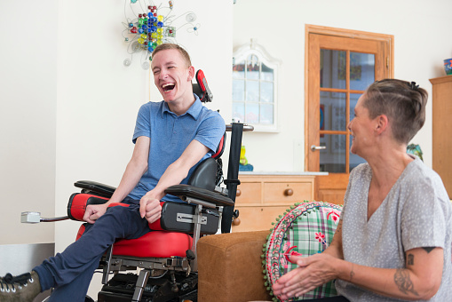 laughing boy in wheelchair with caregiver