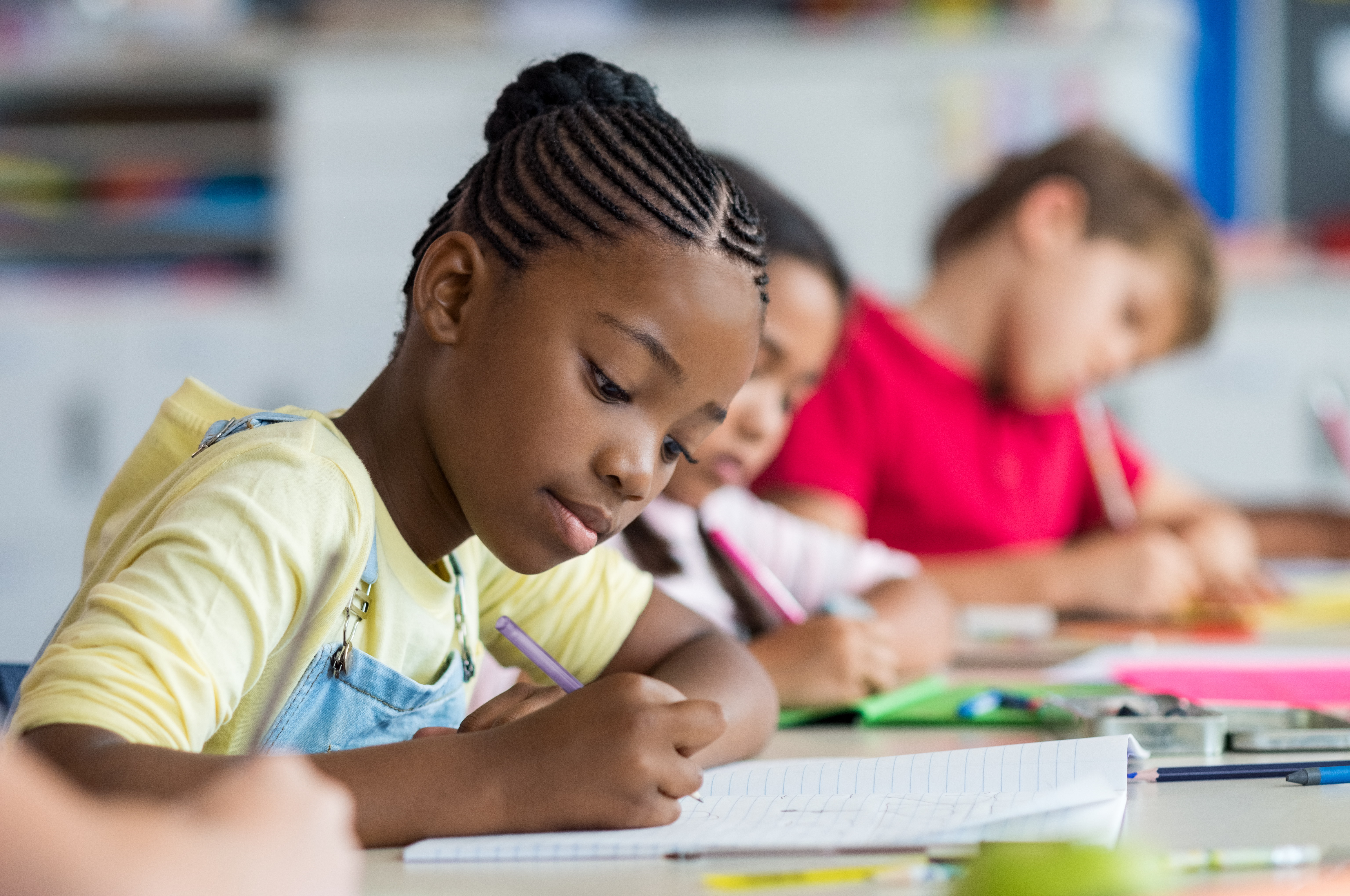 three students in classroom looking at their work