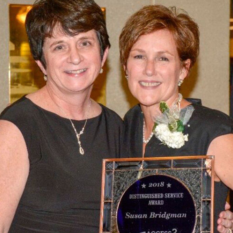 two smiling women holding award