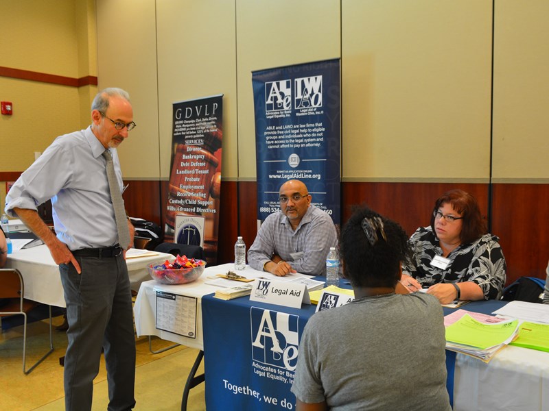 three people sitting, one person standing, at information fair table