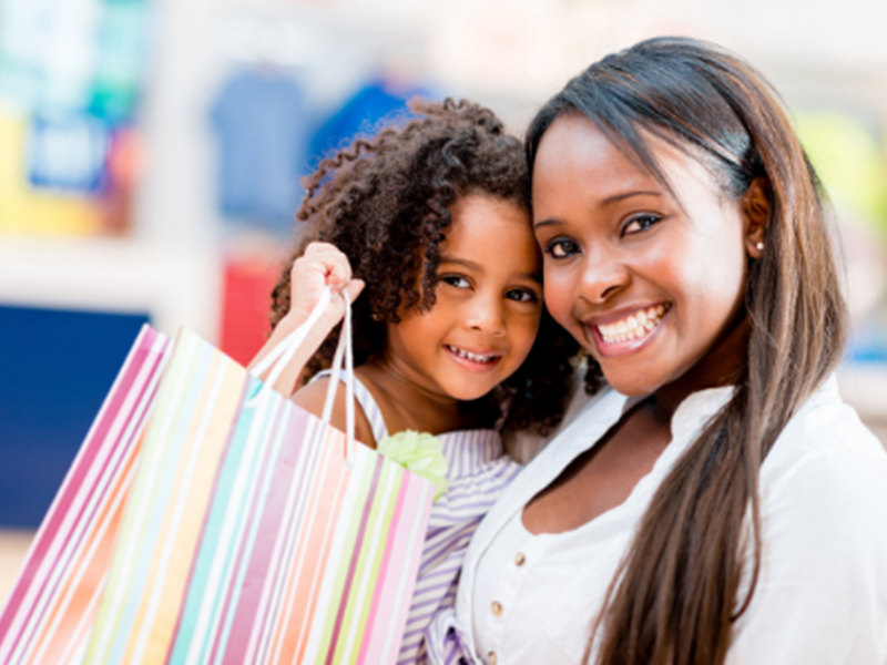 smiling woman holding daughter, smiling daughter holding colorful striped gift bag