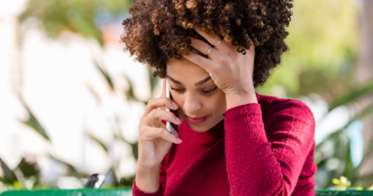 woman holding head in hand, talking on phone