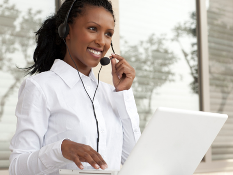 smiling woman wearing headset and using computer
