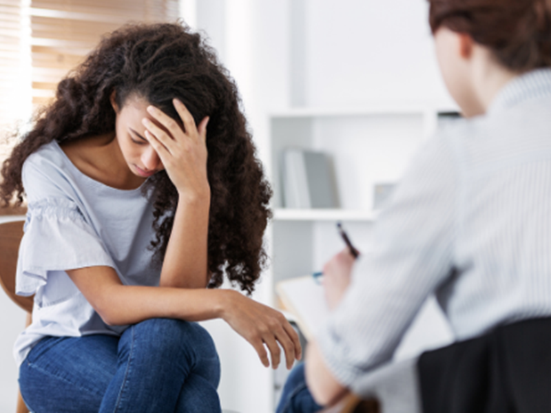 woman holding head in hand, meeting with woman wearing suit