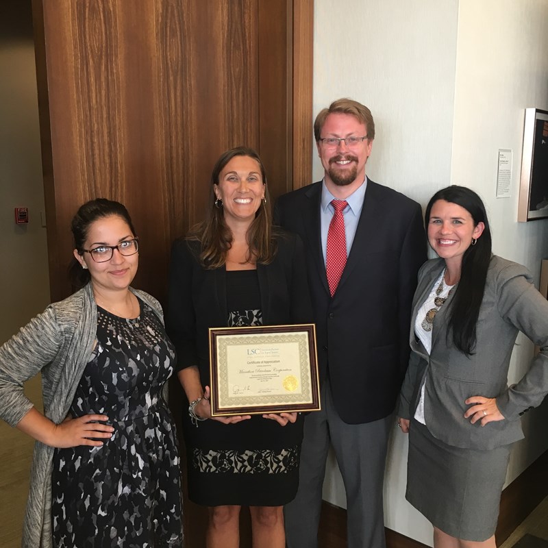 three women and one man holding award certificate