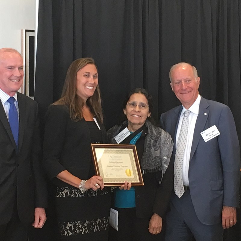 four people holding award certificate