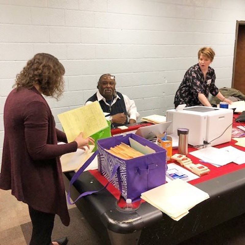 three people at table with boxes of paperwork