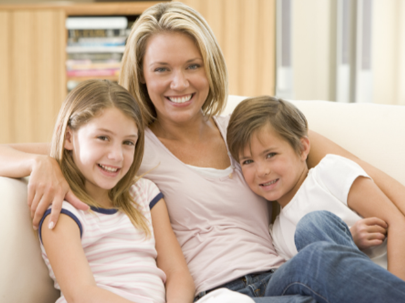 woman with two children, all smiling, on sofa at home