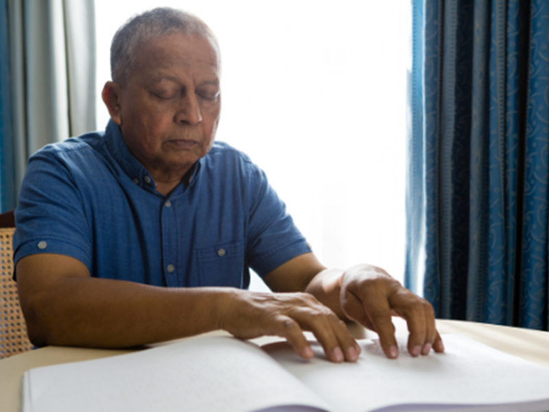blind man at home, reading braille